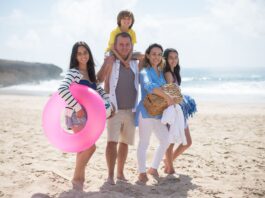 Uśmiechnięta pięcioosobowa rodzina na słonecznej plaży w Portugalii
